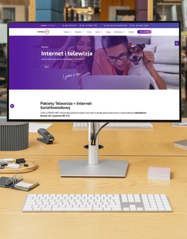 Monitor na biurku z wyświetloną stroną Speed‑Net przedstawiającą ofertę internetu i telewizji światłowodowej